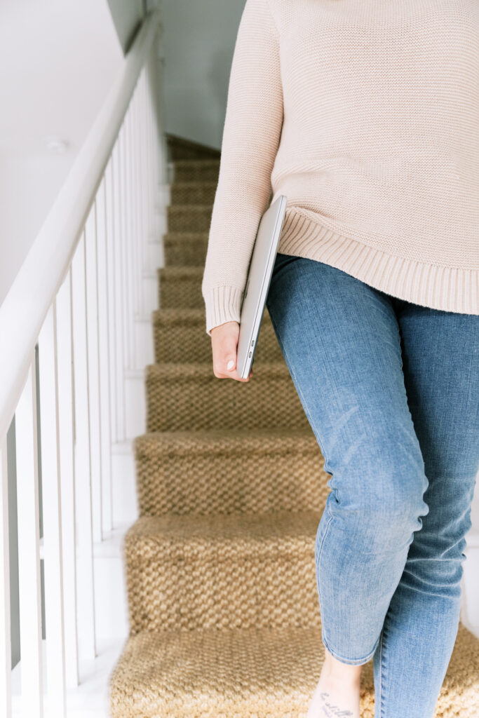 woman walking down the stairs with laptop in hand