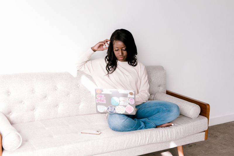 Storytelling strategist sitting on couch as she types on laptop.